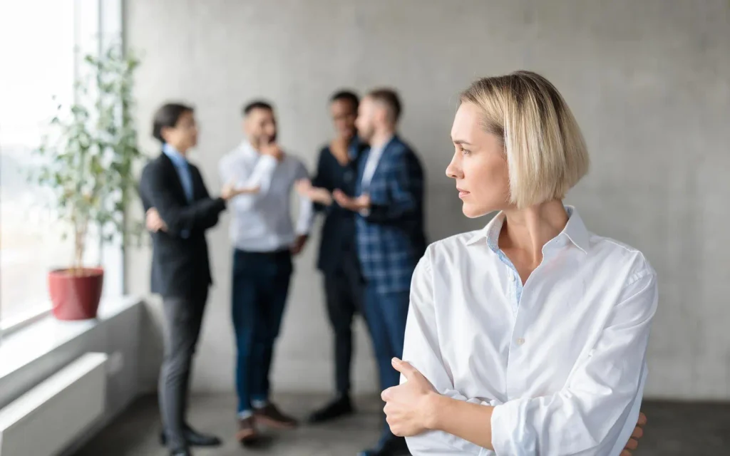 upset woman at work with four men talking behind her back