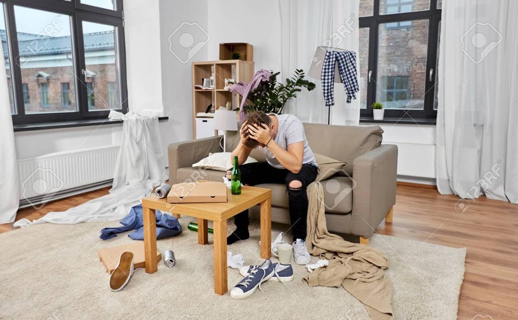 worried man sitting in a messy room