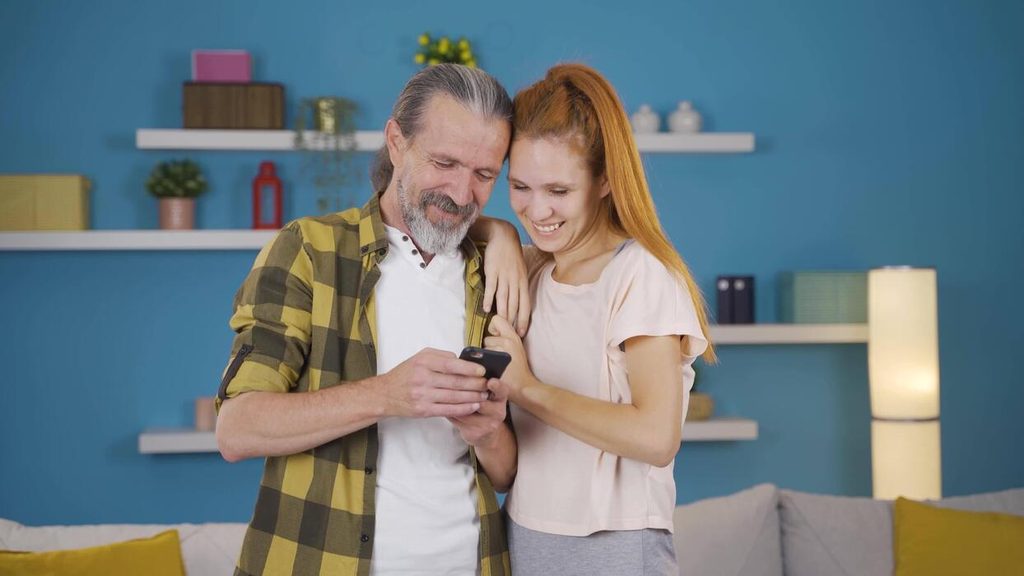 man and woman smiling while looking at the phone