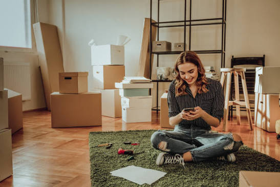 a woman sitting on the floor with moving boxes around her