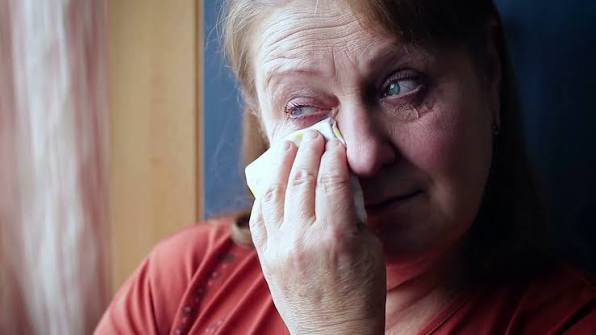 upset woman crying wiping her tears with a handkerchief