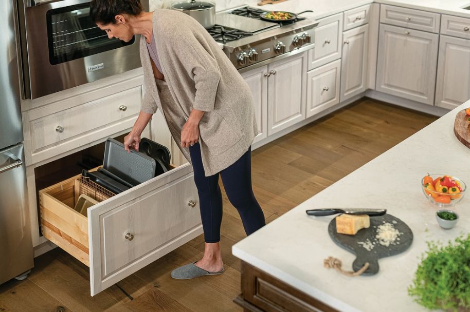 woman taking a pan from a kitchen cupboard