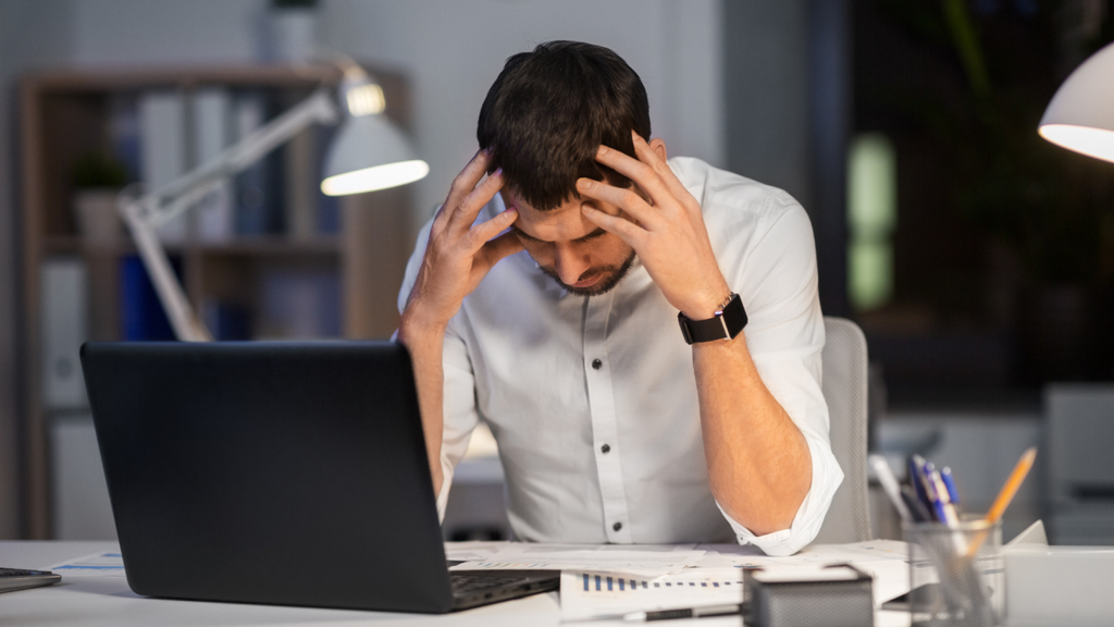 worried man holding his head at an office desk
