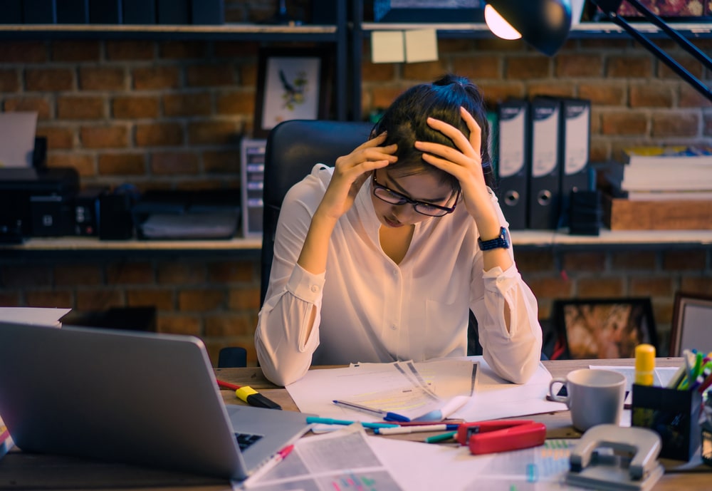 worried woman holding her head at an office desk